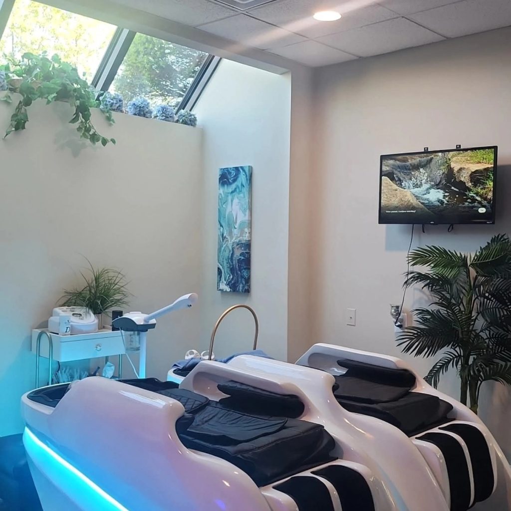 Padded scalp-treatment bed illuminated by blue light in a Destani Trichology treatment room.
