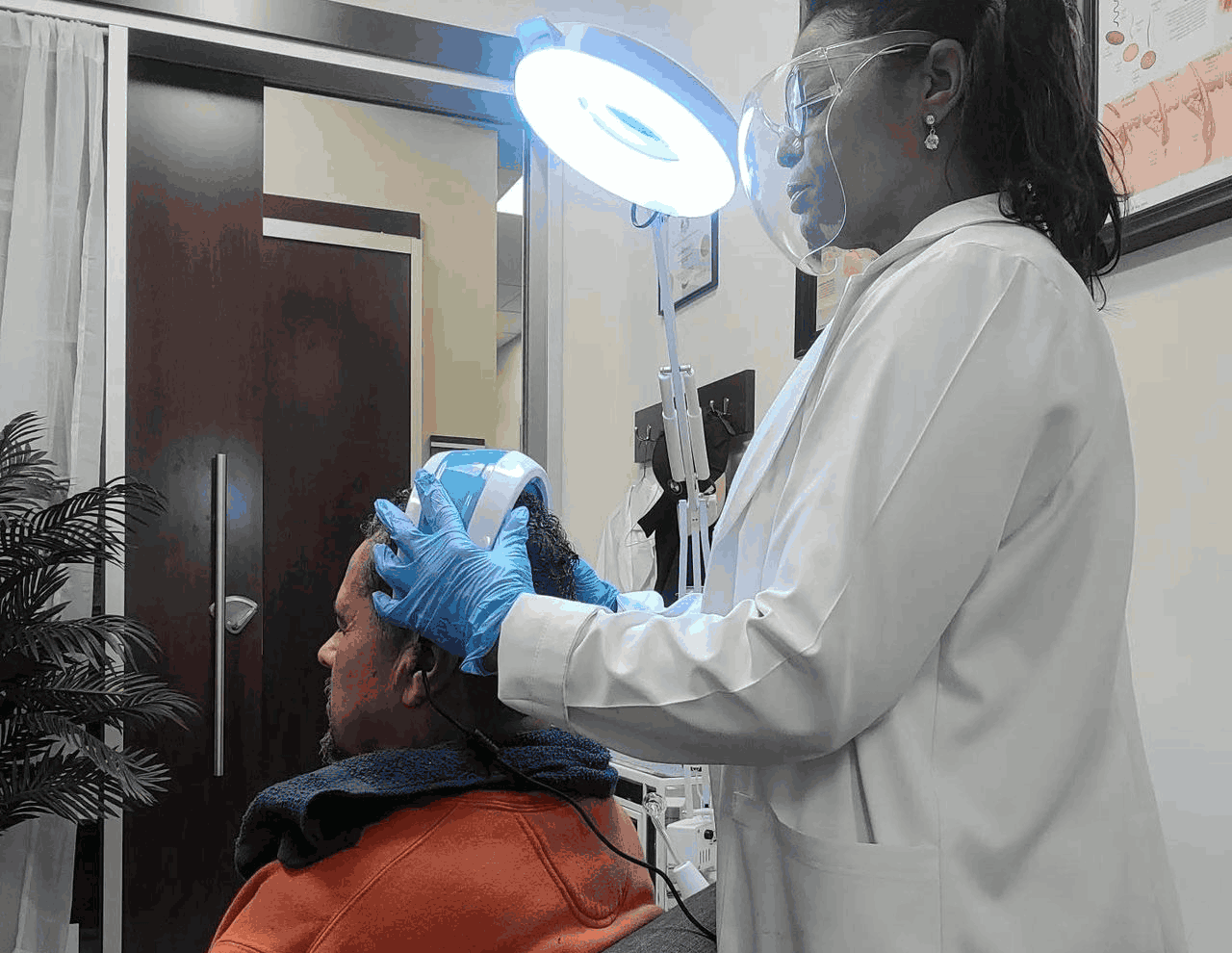 Trichology practitioner using a handheld scanner to examine a client's scalp.
