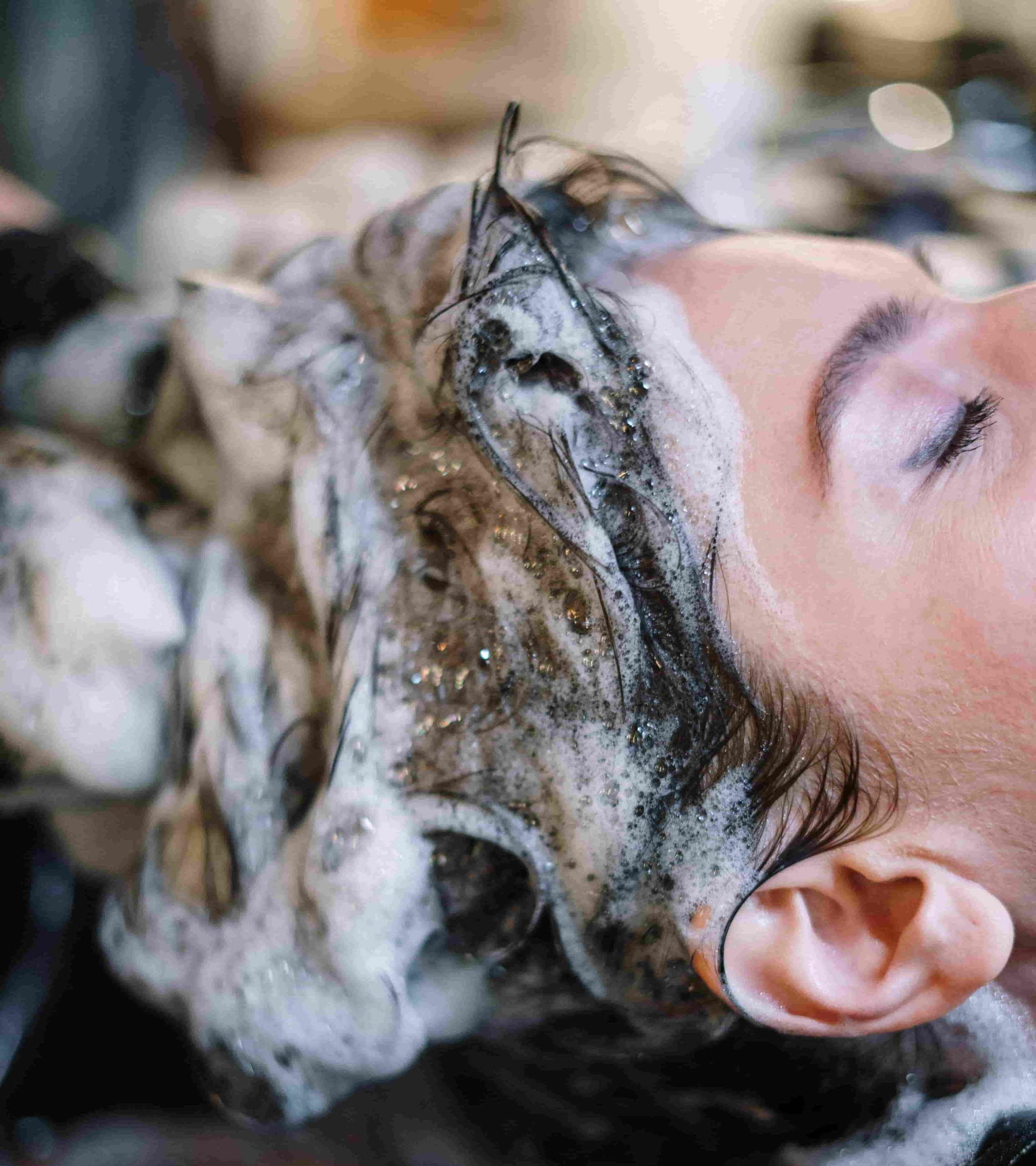 Close-up of a woman receiving a foaming scalp and hair treatment.